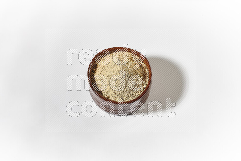 A brown pottery bowl full of ground ginger powder on white background