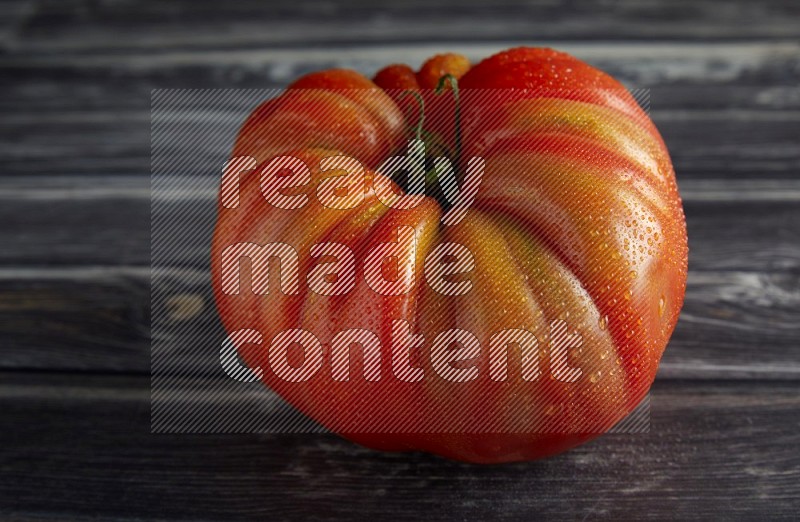 45 degree single heirloom tomato on a textured grey wooden background