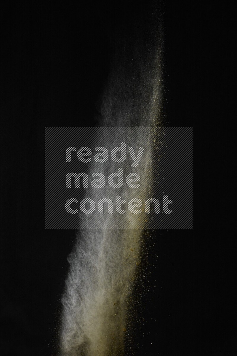 A side view of yellow powder explosion on black background