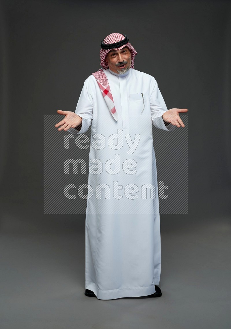 Saudi man with shomag Standing Interacting with the camera on gray background