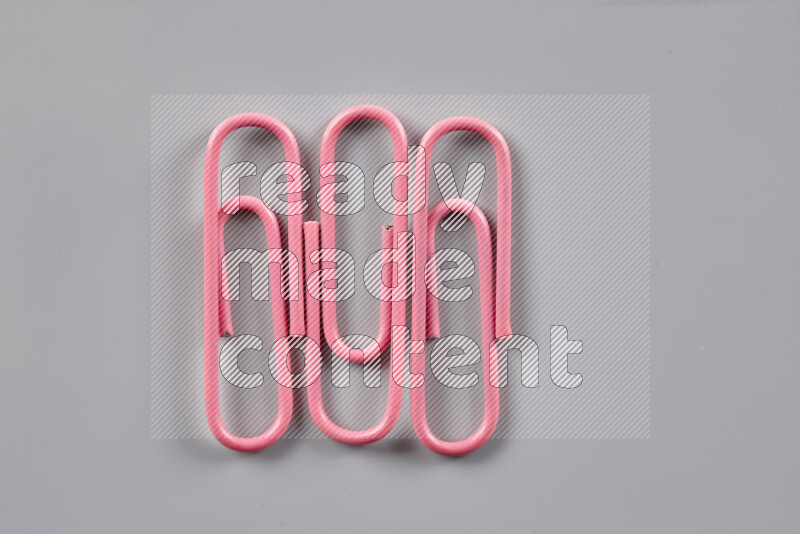 Pink paper clips isolated on a grey background
