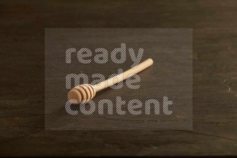 Wooden honey dipper on black slate background
