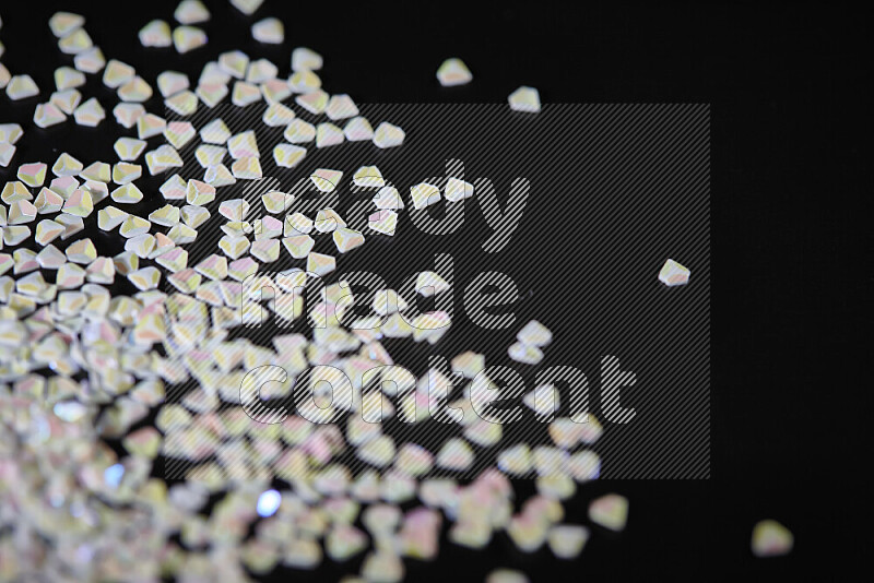 Colorful plastic shards for decoration scattered on a black background