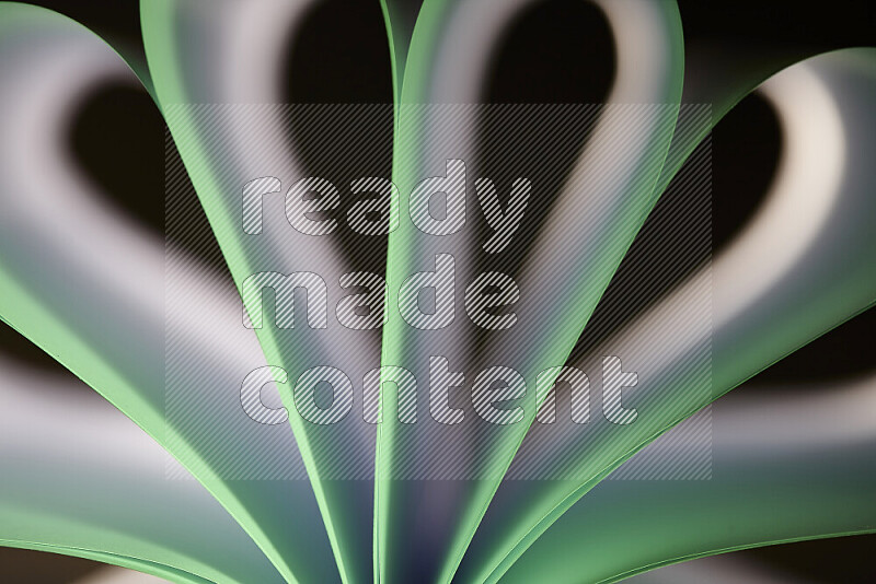 An abstract art piece displaying smooth curves in white and green gradients created by colored light