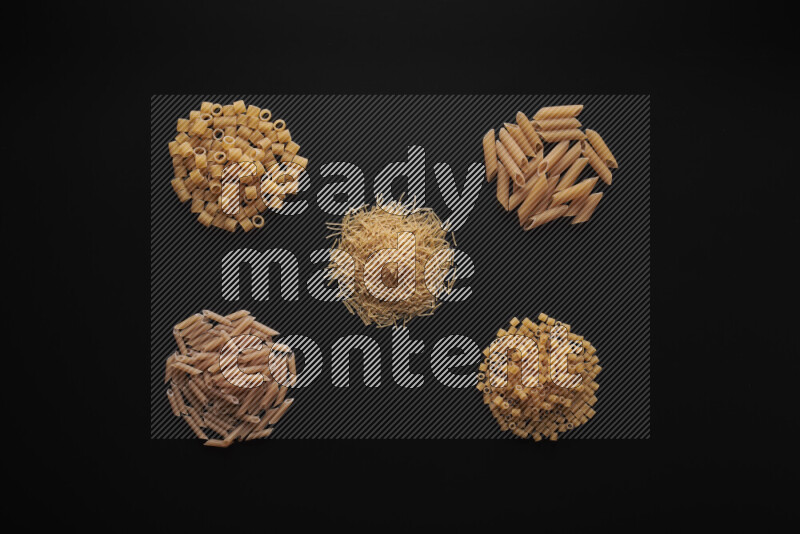 Different pasta types in bunches on black background