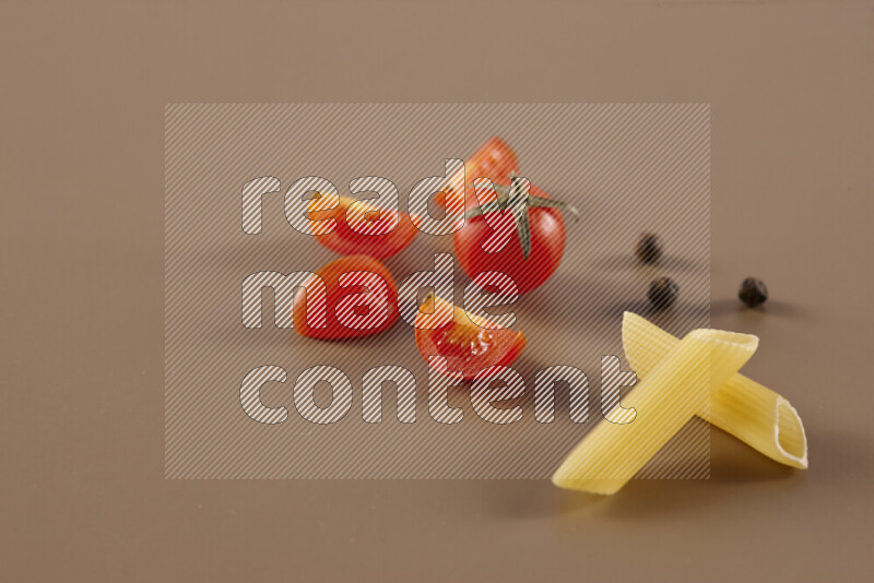 Raw pasta with different ingredients such as cherry tomatoes, garlic, onions, red chilis, black pepper, white pepper, bay laurel leaves, rosemary and cardamom on beige background
