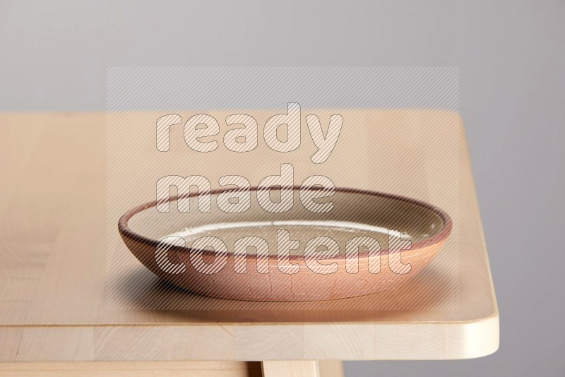 multi-colored pottery Plate on a wooden table edge