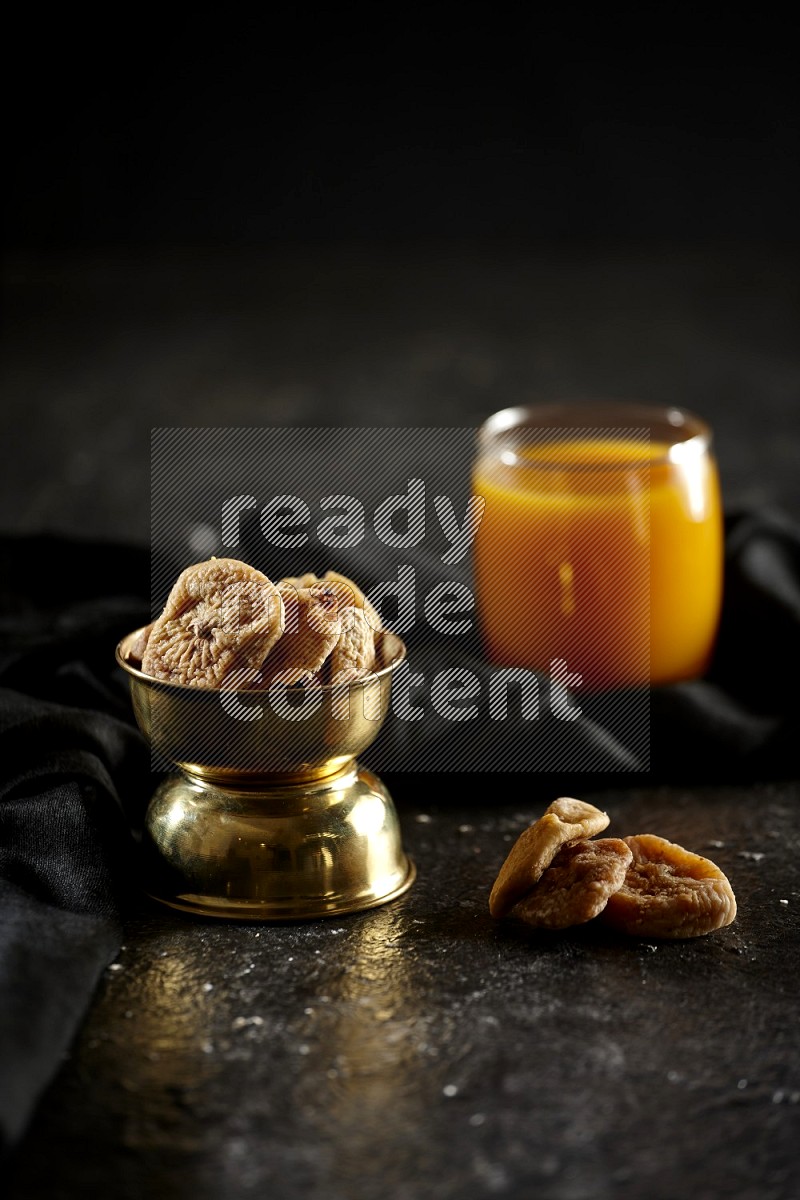 Dried fruits in a metal bowl with qamar eldin and a napkin in a dark setup