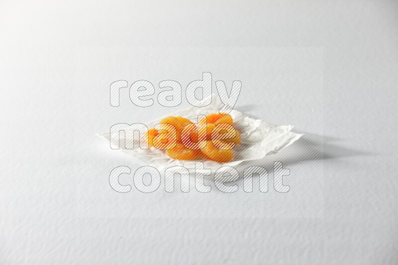 Dried apricots on a crumpled piece of paper on a white background in different angles