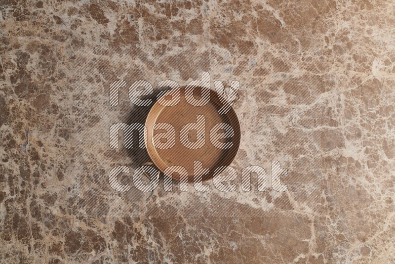 A small copper pan on beige marble background