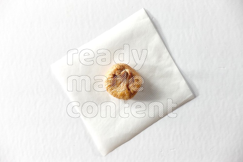 A dried fig on a piece of paper on a white background in different angles