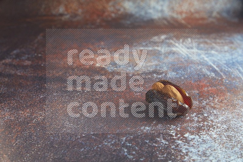 one almond stuffed madjoul date on a rustic reddish background