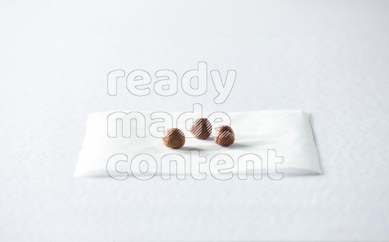 3 peeled hazelnuts on a piece of paper on a white background in different angles