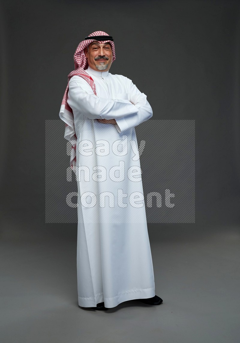 Saudi man with shomag Standing Interacting with the camera on gray background