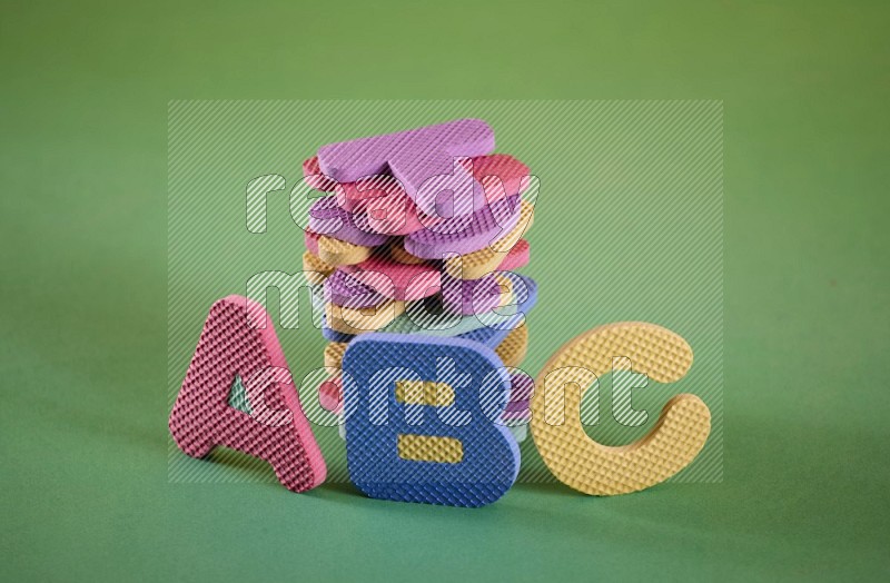 Alphabets letters in foam puzzle for kids on yellow and green background in different angles (kids toys)