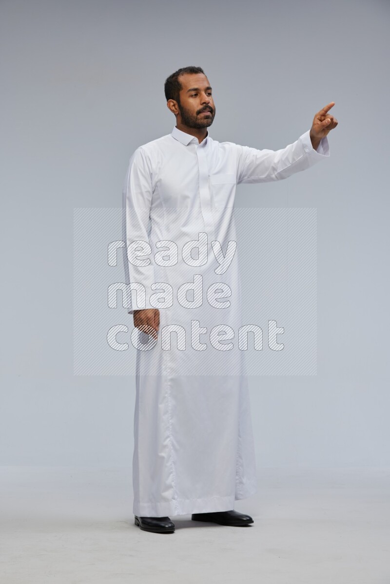 Saudi man Wearing Thob standing interacting with the camera on Gray background