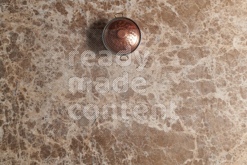 A small copper pot on beige marble background