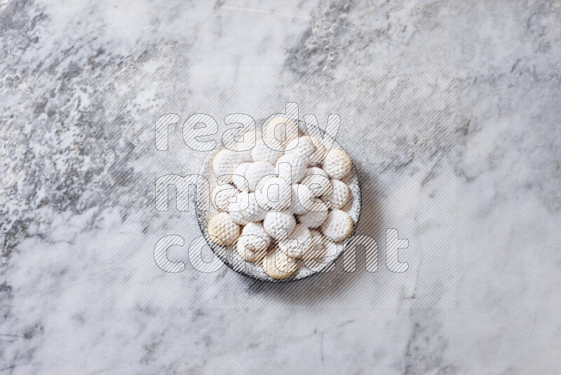 كحك في صحن فخار أسود على خلفية رخام رمادي