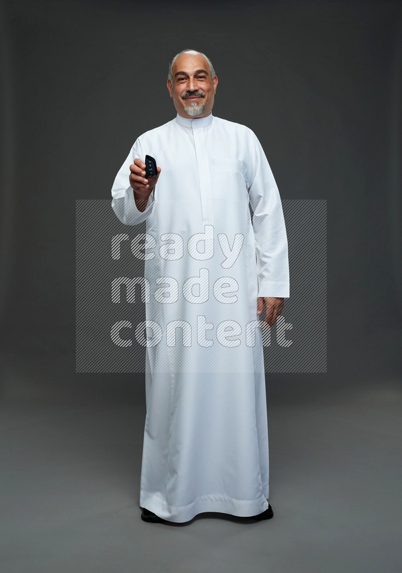 Saudi man without shomag Standing holding car key on gray background