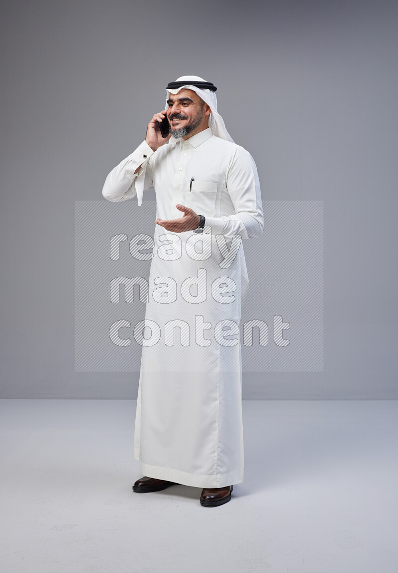 رجل سعودي يرتدي ثوب وشماغ ابيض يتحدث بهاتفه الجوال