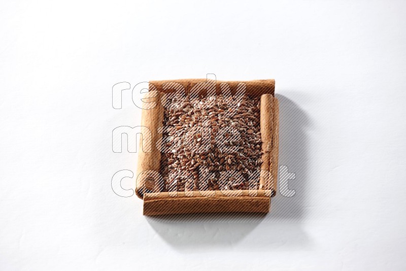 A single square of cinnamon sticks full of flaxseeds on white flooring
