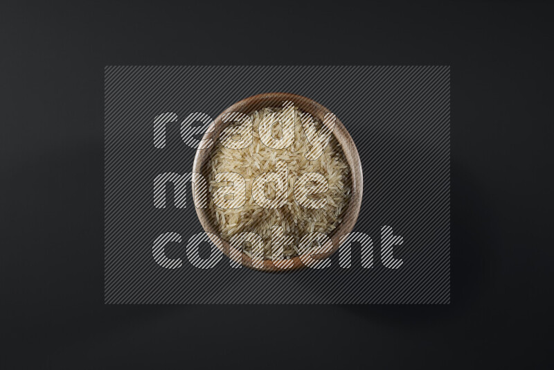 Basmati golden rice in a wooden bowl on grey background