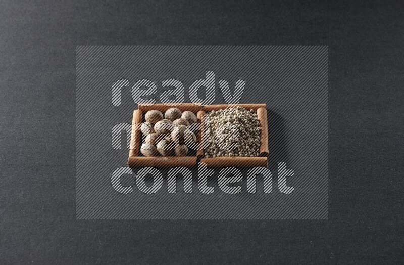 مربعان من أعواد القرفة ممتلئان بجوزة الطيب وحبوب الفلفل الأبيض علي خلفية سوداء