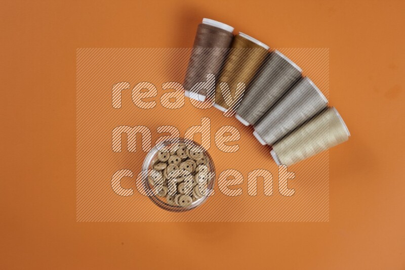 A brown collection of sewing and tailoring tools arranged on a orange background