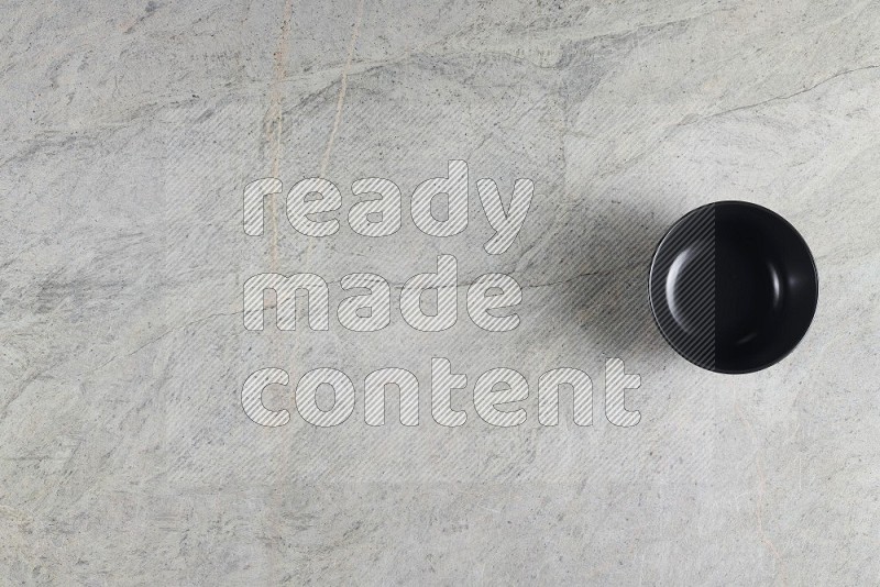 Top View Shot Of A Black Ceramic Bowl On Grey Marble Flooring