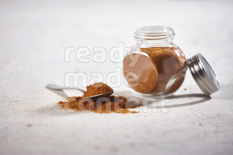 A glass jar full of ground paprika powder on white background