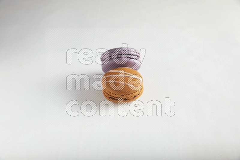 45º Shot of of two assorted Brown Irish Cream, and Purple Blueberry macarons on white background