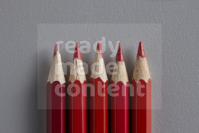 مجموعة من أقلام الرصاص الملونة مرتبة لتعرض تدرجا من الألوان الحمراء علي خلفية رمادية
