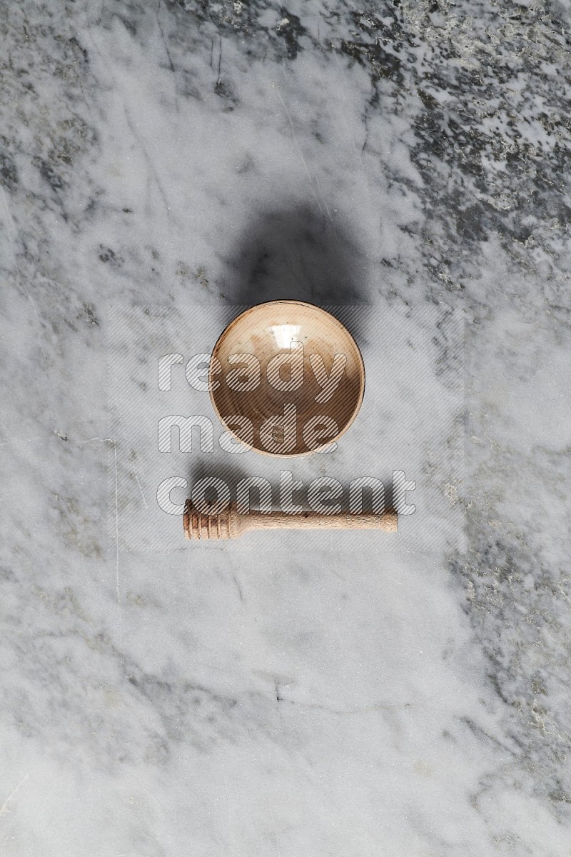Beige Pottery Bowl with wooden honey handle on the side on grey marble flooring, Top view
