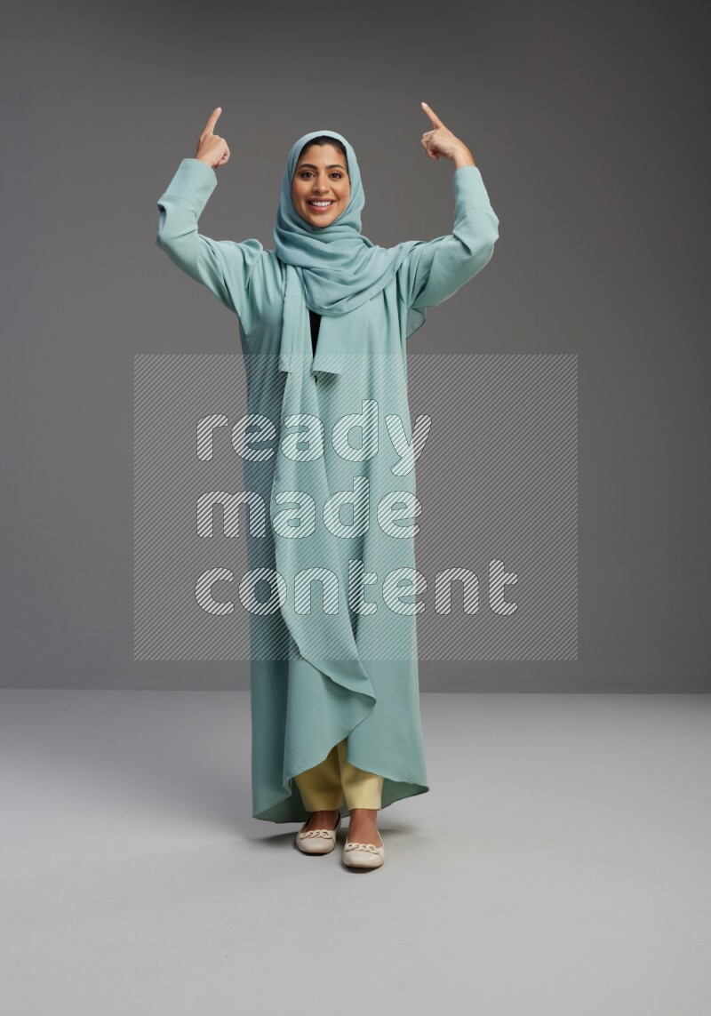 Saudi Woman wearing Abaya standing interacting with the camera on Gray background