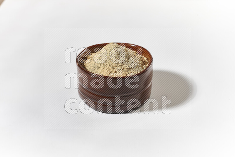 A brown pottery bowl full of ground ginger powder on white background