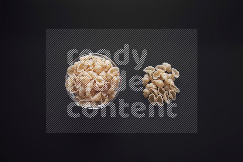 Snails pasta in a glass bowl on black background