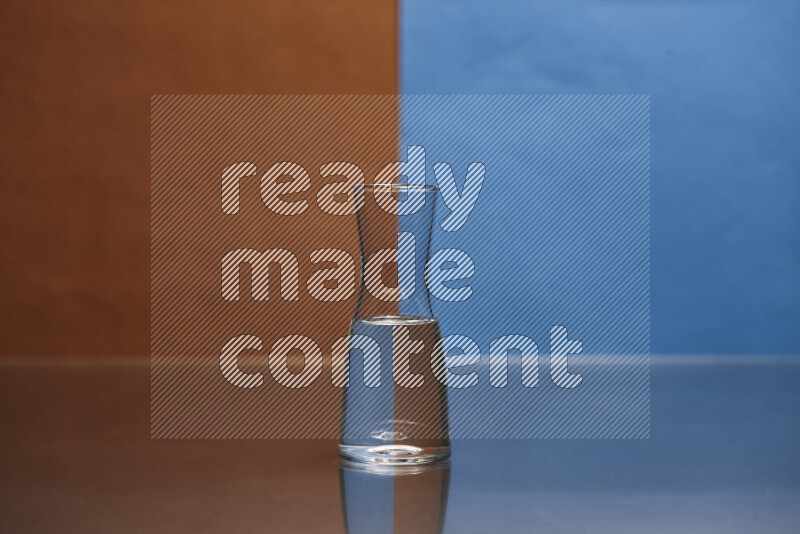 The image features a clear glassware filled with water, set against brown and blue background