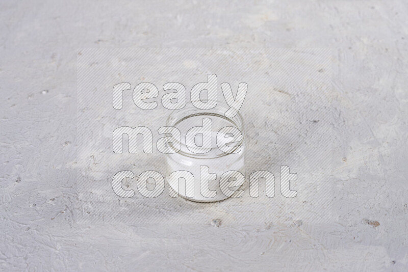 A glass jar full of fine table salt on white background