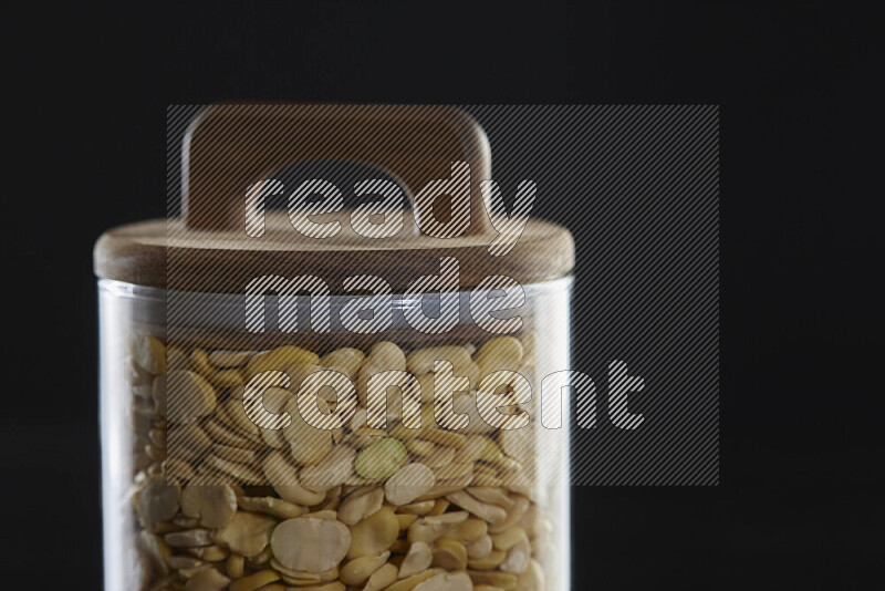 Crushed beans in a glass jar on black background