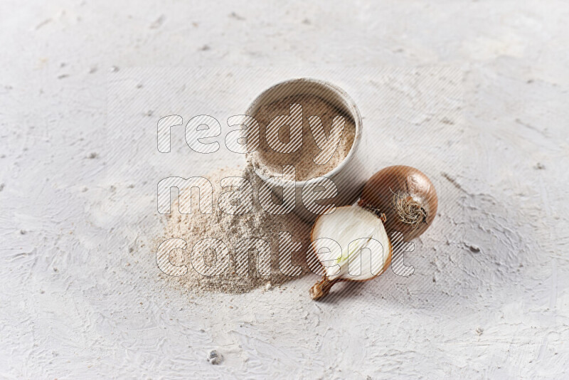 A beige pottery bowl full of onion powder with fallen powder from it on white background