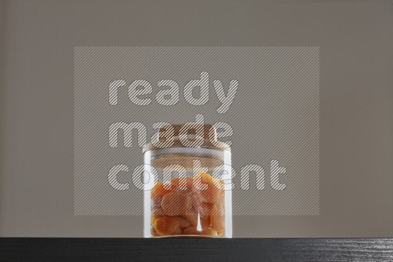 Dried apricots in a glass jar on black background