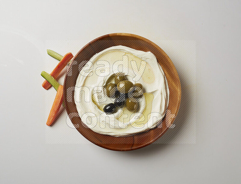 Lebnah garnished with whole olives in a wooden plate on a white background