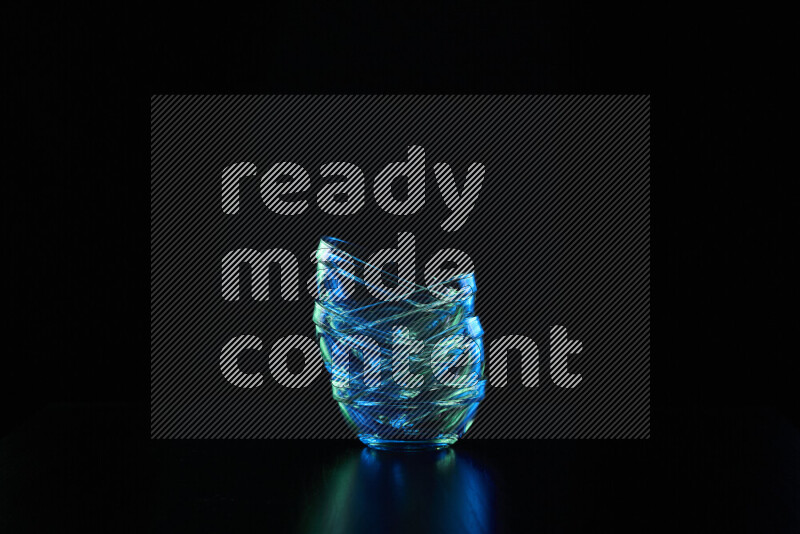 Glassware with rim light in blue and green against black background