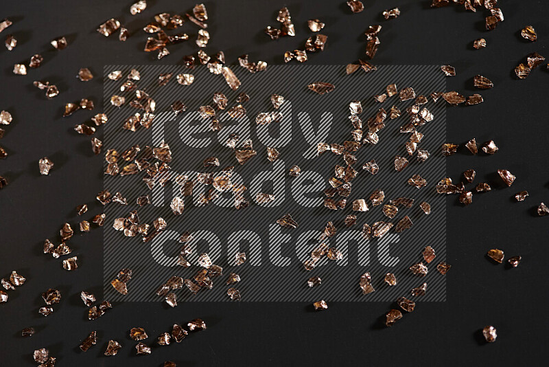 Bronze shimmering fragments of glass scattered on a black background