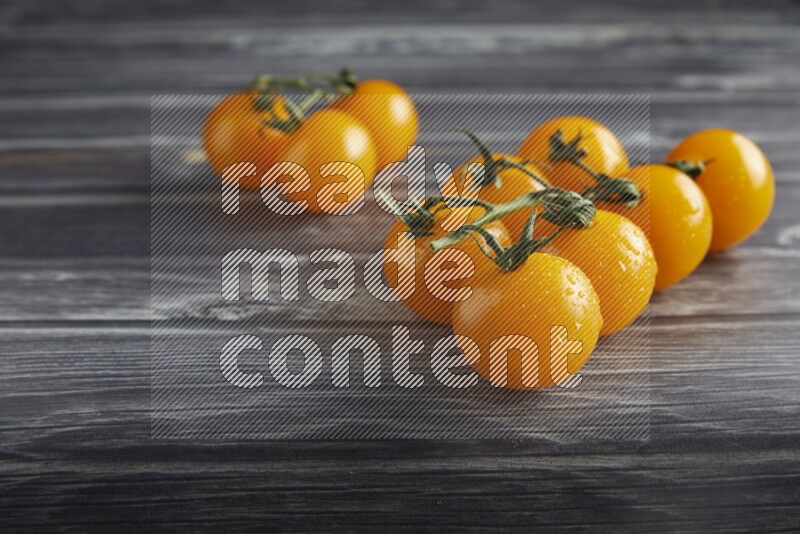 Yellow cherry tomato vein on a textured grey wooden background 45 degree
