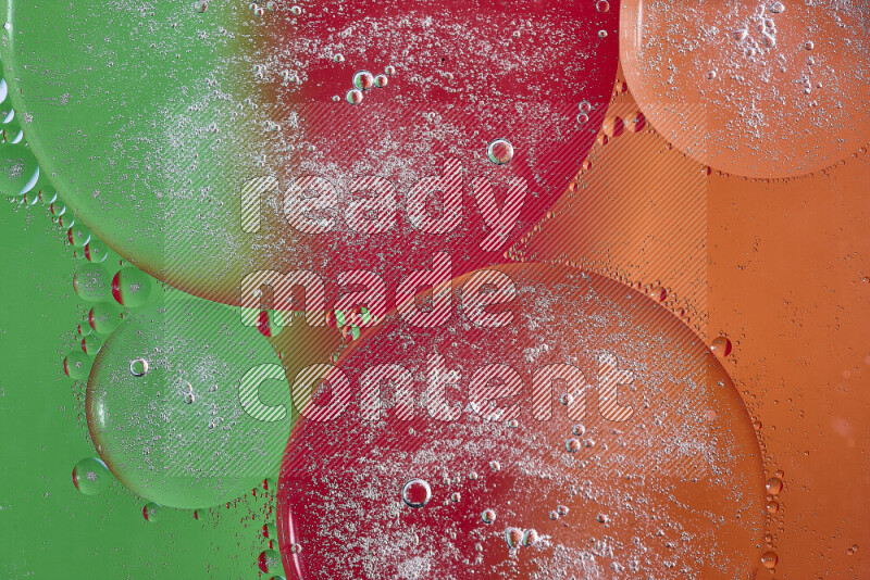 Close-ups of abstract oil bubbles on water surface in shades of orange, green and red