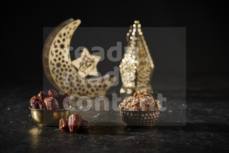 Dates in a metal bowl with walnuts beside golden lanterns in a dark setup