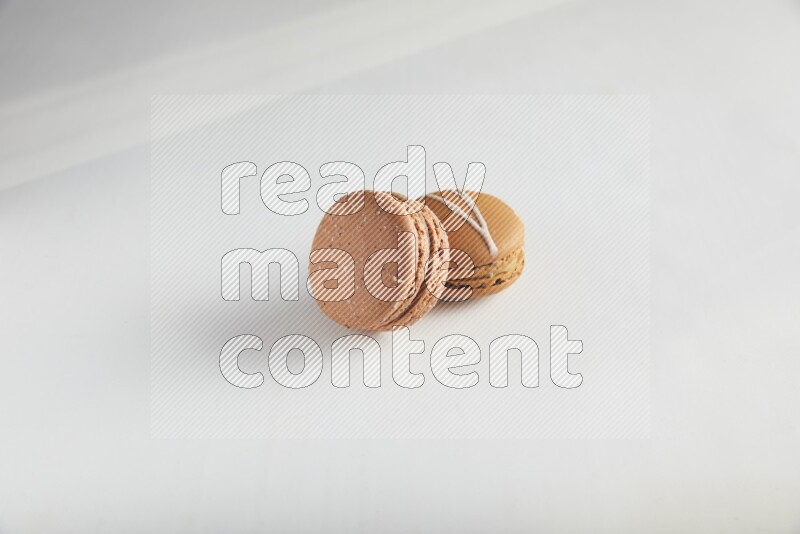 45º Shot of of two assorted Brown Irish Cream, and Brown Hazelnuts macarons on white background