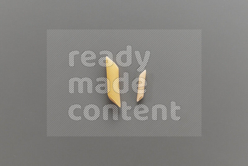 Penne pasta with other types of pasta on grey background