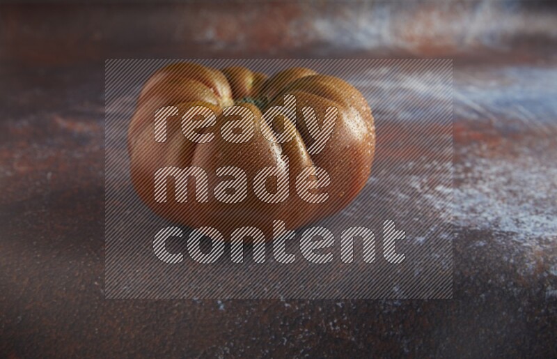 45 degree single heirloom tomato on  a textured reddish rustic metal background
